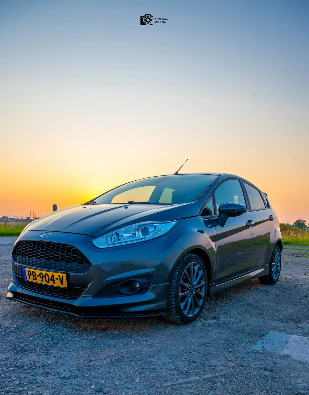 Ford Fiesta schuin van voren onder een lucht die verloopt van blauw naar oranje bij zonsondergang
