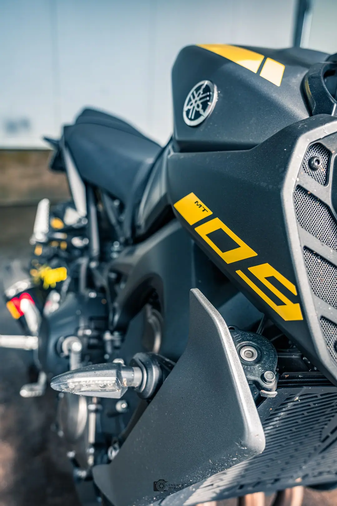 Close-up van de zwarte tank en zijkap van een Yamaha MT-09 met gele MT-09-belettering en richtingaanwijzer, met een onscherpe achtergrond.