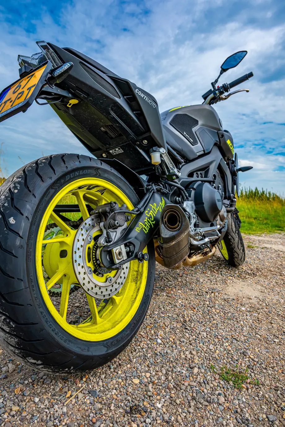 Yamaha MT-09 laag van achteren gefotografeerd, met het brede achterwiel met gele velg prominent op de voorgrond en een blauwe lucht.