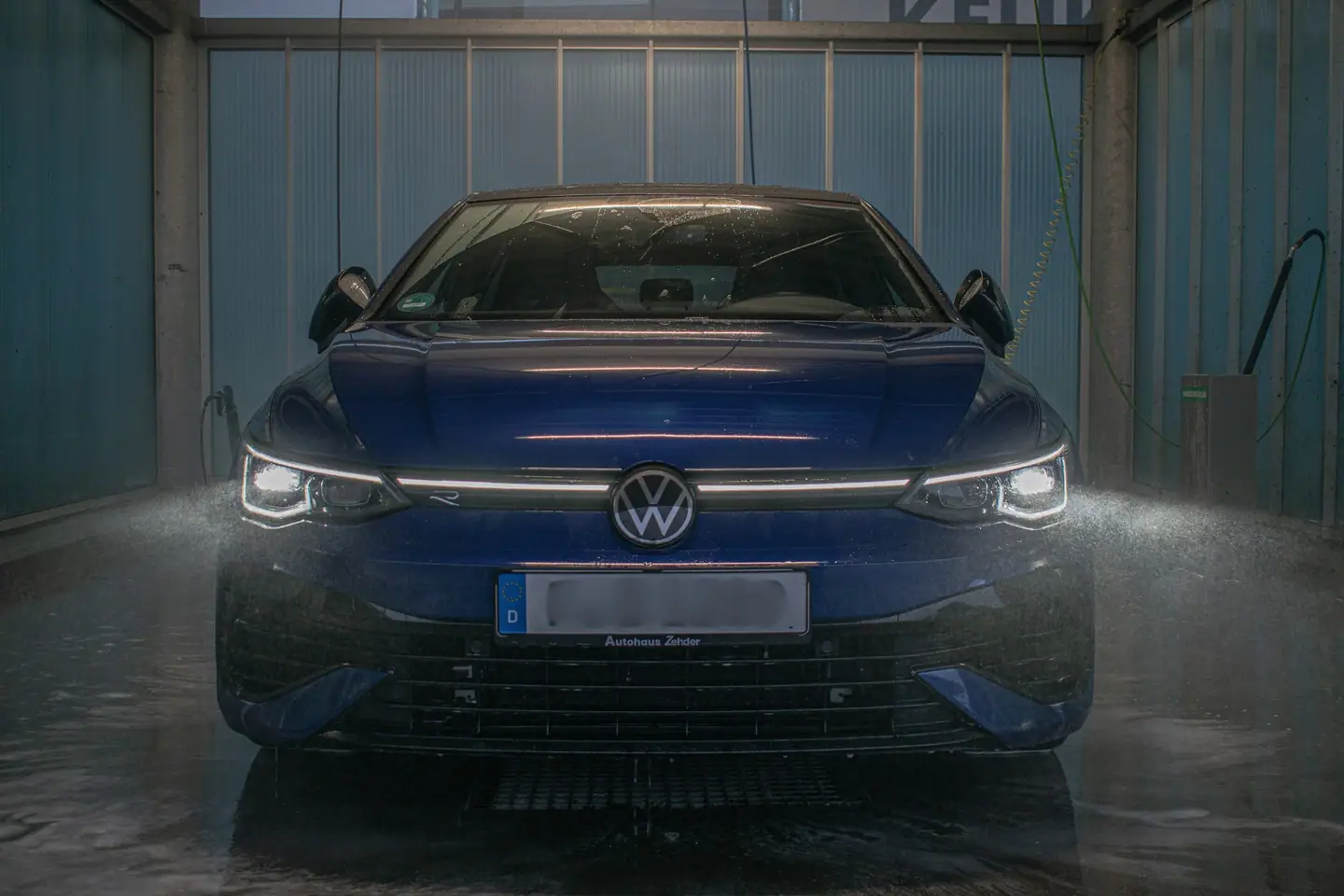 Volkswagen Golf R recht van voren in een wasbox, omringd door een nevel van waterdruppels